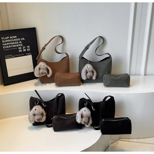Detail view of a 4-piece minimalist suede shoulder bag set with rabbit charms and pouches