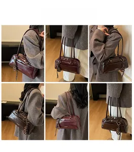Detail view of burgundy leather pillow bag with double straps and metal pendant charm