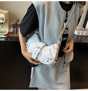 Detail of white crocodile embossed crescent bag with silver rivets and metal buckle