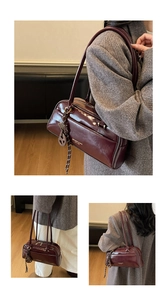 Detail of burgundy patent leather bowling bag showing glossy finish and shoulder strap