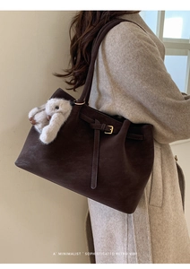 Détail d'un grand sac cabas vintage marron chocolat avec boucle dorée et breloque lapin