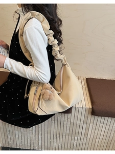 Detail of cream tote bag featuring ruffled cloud strap and cute plush bear charm