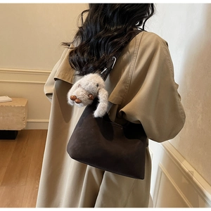 Brown suede underarm bag with cute plush rabbit charm on a trench coat model