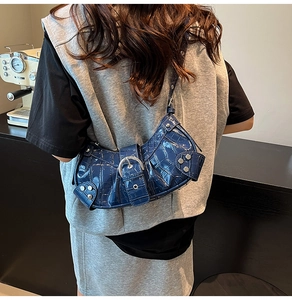 Detail of dark blue crocodile pattern shoulder bag with silver metallic buckle on model