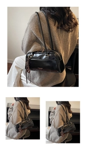 Close-up of black glossy leather shoulder bag with gold hardware and logo detail