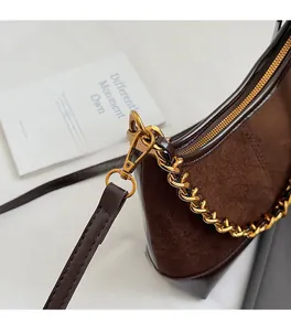 Detail of dark brown patchwork shell bag with suede texture and golden chain strap