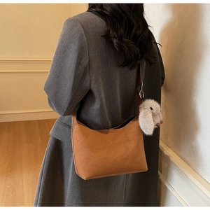 Close-up of caramel retro shoulder bag with suede texture and plush rabbit pendant