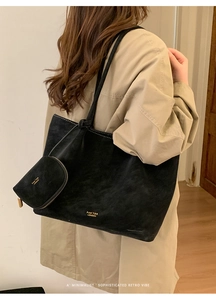 Detalle de bolso tote de ante negro con logotipo dorado y mini monedero a juego