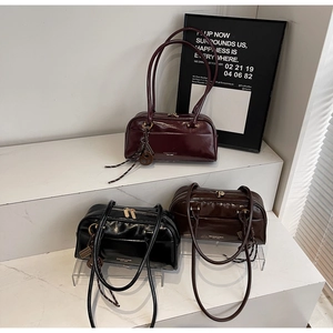 Three glossy leather pillow bags in burgundy, black and coffee on decorative steps