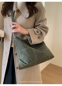 Detalle de bolso tote de ante verde oscuro con costuras en contraste y etiqueta moda