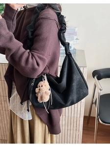 Detail of black scrunchie shoulder bag with a plush bear charm on a minimalist model
