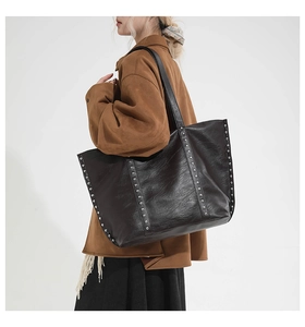 Detailed side view of large black tote bag with silver rivets and leather texture