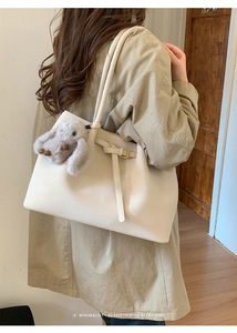 Détail d'un grand cabas crème avec boucle élégante et charmant pendentif lapin en peluche