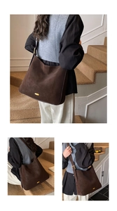 Close-up of matte dark brown leather tote featuring a vintage oval gold metal ornament