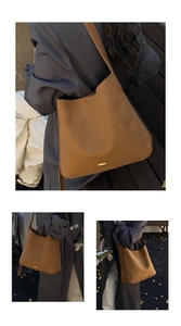 Detail of dark brown leather tote bag featuring an oval gold buckle and wide strap