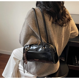 Détail du sac bowling en cuir noir brillant avec fermetures éclair dorées et logo