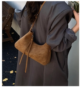 Close-up of brown suede crossbody bag with long leather tassels on a casual shoulder bag