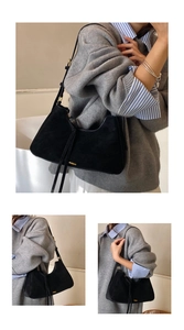 Detail of black suede hobo bag with gold hardware and long decorative tassels on zipper