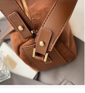 Detailaufnahme einer braunen Wildleder-Handtasche mit hochwertigen goldenen Metallbeschlägen