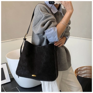 Black matte suede tote bag with golden oval buckle detail shown on shoulder