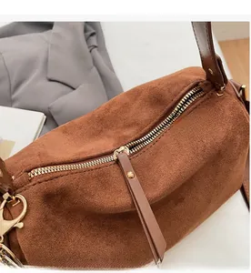 Detaillierte Makroansicht des Metallreißverschlusses und Ledergriffs der braunen Wildledertasche