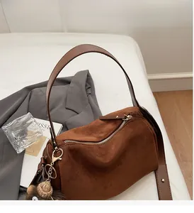 Detail der dunkelbraunen Wildleder-Boston-Tasche mit Ledergriffen und Plüsch-Anhänger