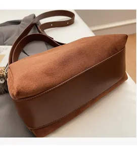 Detail der braunen matten Ledertasche mit Plüsch-Anhänger und verstellbarem Gurt