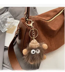 Detailansicht eines braunen Plüschmonsters mit Strickmütze an einer matten Tasche