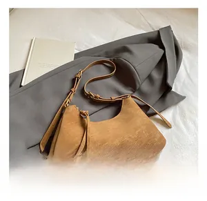 Macro view of brown suede crescent bag featuring retro gold hardware and fringe detail