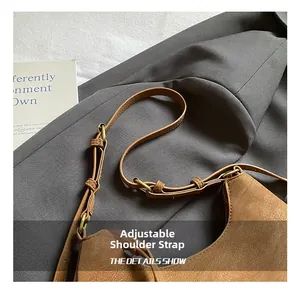 Close-up of the adjustable leather strap with antique brass buckle on a brown tote bag