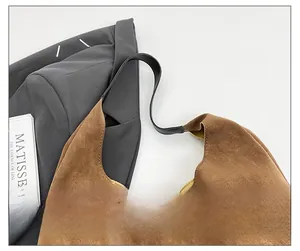 Detailed top view of a brown suede hobo bag styled on a grey blazer with art books