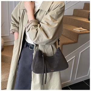Detail of vintage brown leather underarm bag with long fringe charm and gold metal plate