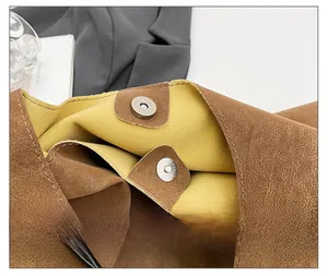 Macro detail of the magnetic button closure on a vintage brown leather tote bag