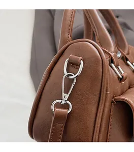 Close-up of premium silver metal hardware and smooth brown leather texture on handbag