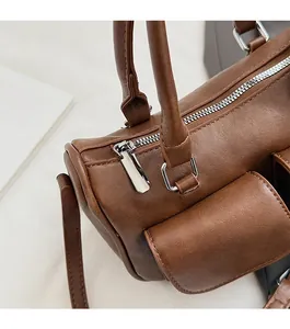 Detail of brown pebbled leather handbag featuring smooth silver zippers and side pocket