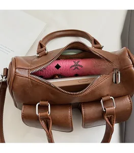 Brown leather boston bag showing spacious interior with open zipper and two front pockets