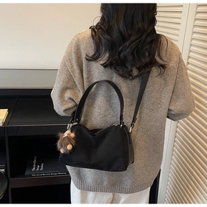 Details der schwarzen Suede-Tasche mit Plüschaffen-Anhänger und verstellbarem Riemen