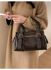 Détail d'un sac à main vintage marron foncé avec boucles en bronze et manteau en laine