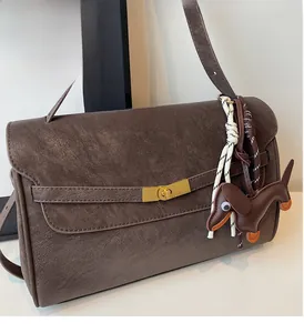 Detail of vintage brown tote bag with gold metal buckle and leather dachshund charm
