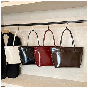 Detail view of large tote bags in four colors with rivet accents and glossy finish
