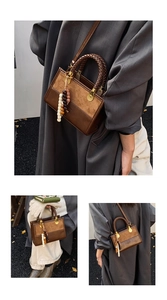 Detail of a brown leather shoulder bag with a woven handle and beaded tassel charms