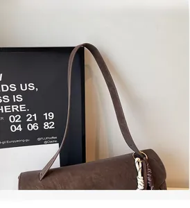 Close-up of a brown leather tote bag with stylish knot charm and durable wide strap