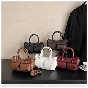 Boston bags in five colors with front pockets and adjustable straps on black desk