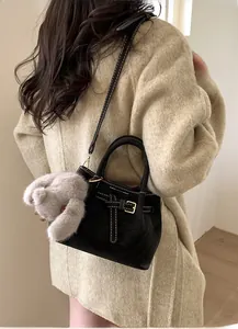 Detail view of black suede bucket bag with contrast white stitching and cute rabbit charm