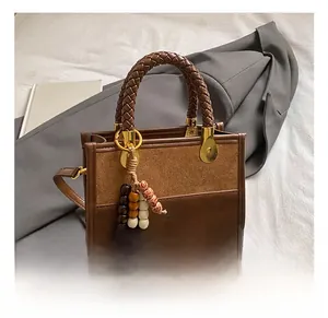 Detail of a brown leather tote with woven handles and decorative bead tassels