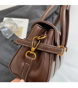 Detail of dark brown leather bag showing gold metal hardware and white contrast stitching
