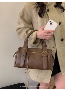 Gros plan sur un sac à main rétro en cuir marron foncé avec boucles et fermeture éclair