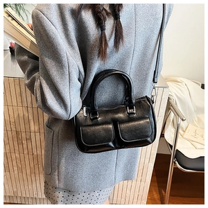 Rear view of black multi-pocket crossbody bag worn by model in a cozy indoor setting