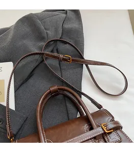 Detail of dark brown leather handbag with adjustable strap and vintage gold hardware