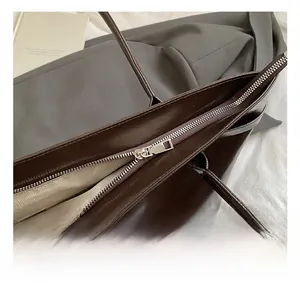 Close-up of silver zipper on dark brown tote bag with herringbone lining and patent finish